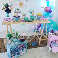 a table filled with lots of decorations and balloons on top of a floor next to a wall