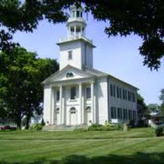 a white church with a steeple surrounded by trees