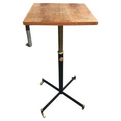 a wooden table with two metal legs and an end table on one side that has wheels attached to it