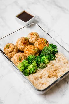 a glass container filled with rice, broccoli and meatballs