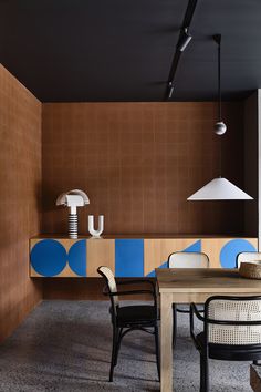 a dining room table and chairs in front of a brown wall with blue circles on it