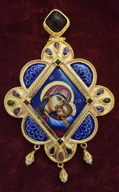 an ornate gold and blue brooch with the image of jesus on it's face