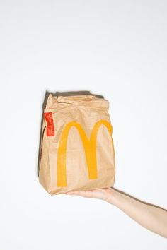 a paper bag with a mcdonald's logo on it being held by a hand