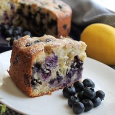 a blueberry muffin on a white plate next to some blueberries