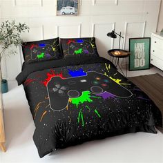 a bed covered in black comforters with colorful paint splatters on the covers