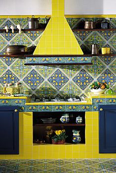 a kitchen with blue and yellow cabinets and tile backsplashes on the wall