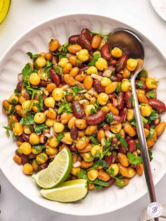 a white bowl filled with chickpeas and garbanzo beans next to a lime wedge