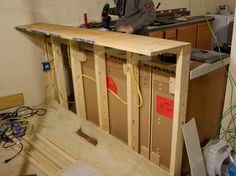 a man is working on an unfinished counter in a room with wood flooring and electrical wires