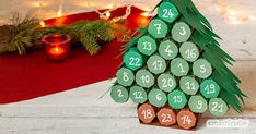 a christmas tree made out of wooden slices with numbers on them and candles in the background