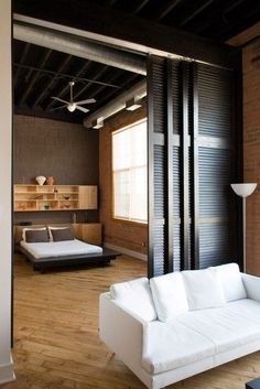 a living room filled with white furniture next to a brick wall and wooden flooring