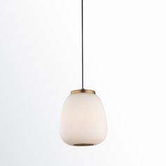 a white and gold light hanging from a black cord on a white wall behind it