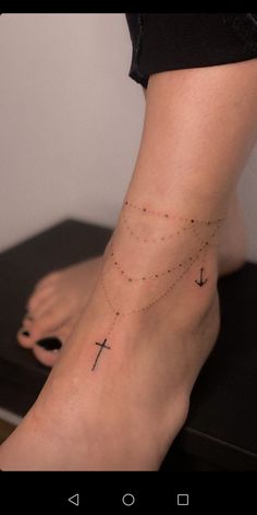 a woman's foot with a cross tattoo on the side of her left leg