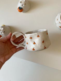 a hand holding a coffee cup in front of small ceramic animals