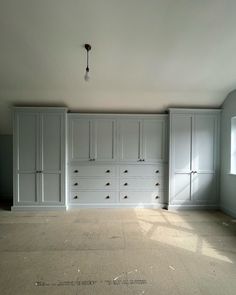 an empty room with white cabinets and drawers