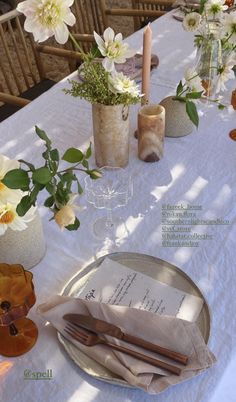 the table is set with candles, flowers and menus for an outdoor wedding reception