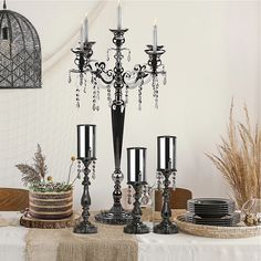 a table topped with black candles and plates