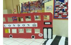 a double decker bus made out of cardboard in a school hallway with decorations on the wall