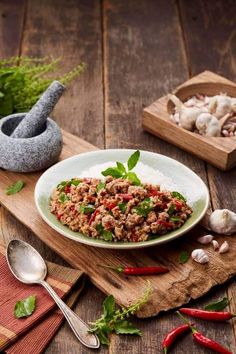 a white plate topped with meat and vegetables on top of a wooden cutting board next to garlic