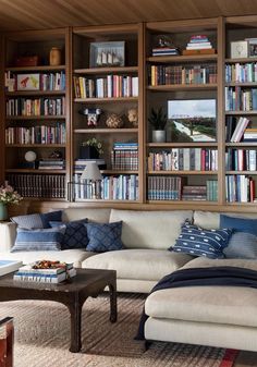 a living room filled with lots of furniture and bookshelves covered in shelves full of books