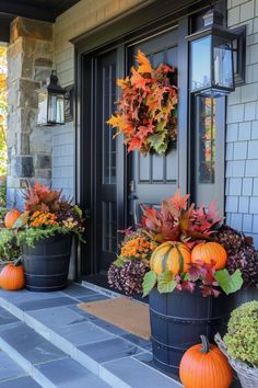 two large planters filled with pumpkins on the front porch