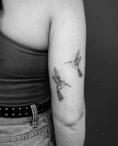 a black and white photo of a woman with a hummingbird tattoo on her arm