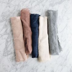 five different colors of scarves laid out on a marble surface