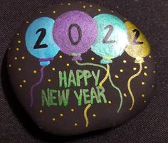 a painted rock with balloons and the number twenty four on it that says happy new year