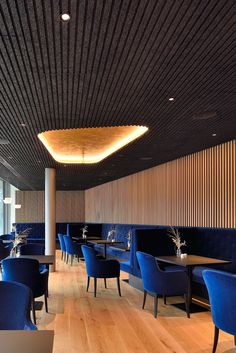 an empty restaurant with blue chairs and wooden tables in the center, along with wood paneling on the walls