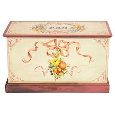 an ornate painted box with fruit and flowers on the front, decorated with ribbon around the lid