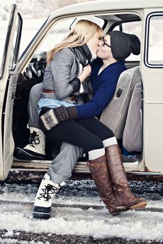 two women sitting in the back of an old car, one is kissing the other