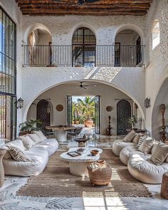 a living room filled with white furniture and lots of windows on top of the walls