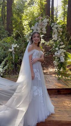 a woman in a wedding dress standing on a wooden platform