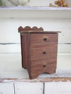 a small wooden dresser sitting on top of a white shelf