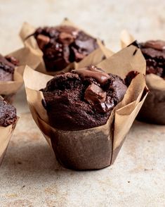 several chocolate muffins sitting on top of each other in brown paper wrappers