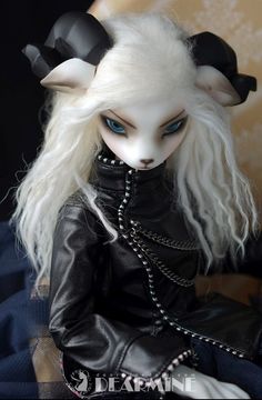 a doll with white hair and blue eyes sitting on a chair wearing a black leather outfit