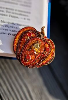 an orange brooch sitting on top of a book