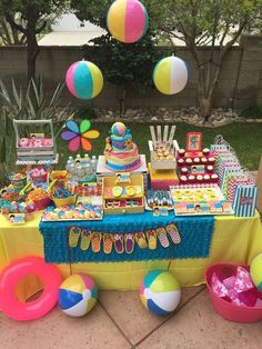 the table is set up for a pool party with beach ball decorations and candy bars