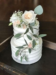 a wedding cake with flowers and greenery on top