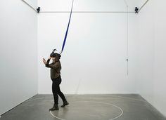 a man holding onto a blue object in an empty room