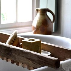 a bathroom sink with soap and toothbrushes in the bathtub next to a window