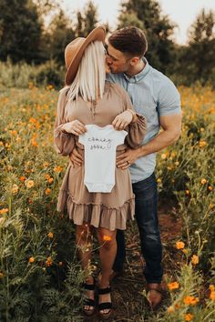 a man and woman standing in a field with flowers