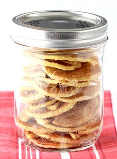 a glass jar filled with cookies on top of a red and white checkered table cloth