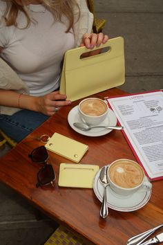 a woman sitting at a table with two cups of coffee and a menu on it