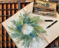 a wreath is sitting on top of an old book and some writing utensils