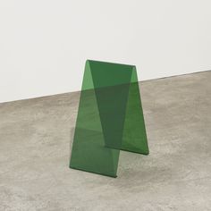 a green sculpture sitting on top of a cement floor