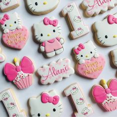 hello kitty cookies are arranged on a white tablecloth with the number one in pink