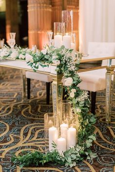 a table with candles, flowers and greenery in front of a mirror on the floor