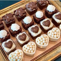 there are many heart shaped chocolates in the tray on the table with marshmallows