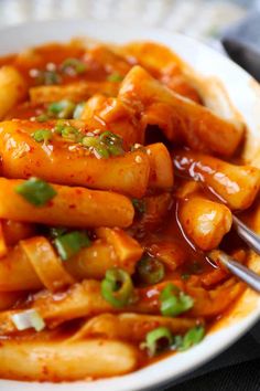 a white plate topped with pasta covered in sauce and garnished with green onions