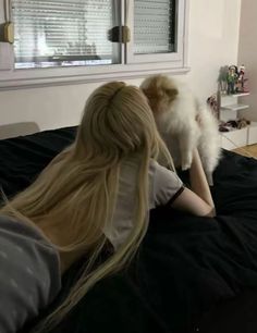 two women sitting on a bed with a dog in their lap and one is holding the other's head